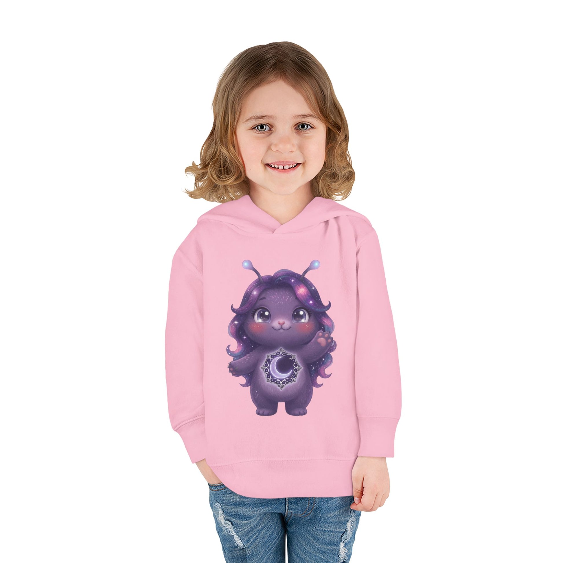 Light pink hoodie featuring a cute purple galaxy creature with antennae, long wavy hair, and a glowing crescent moon emblem on its chest.