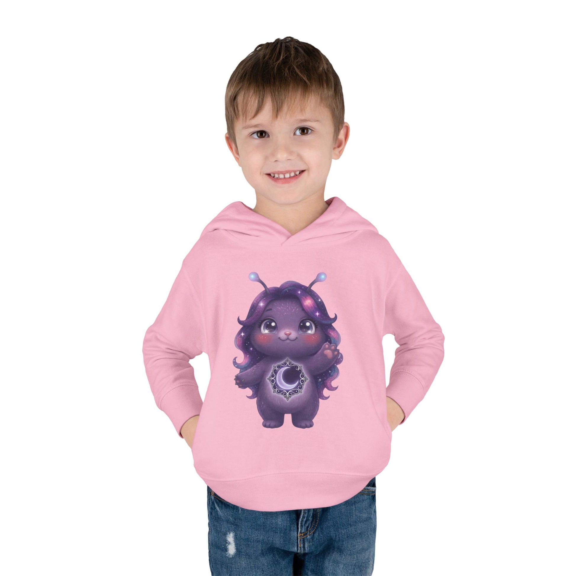 Light pink hoodie featuring a cute purple galaxy creature with antennae, long wavy hair, and a glowing crescent moon emblem on its chest.